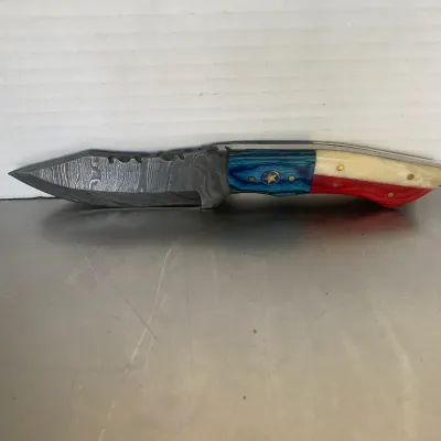 Sale Photo Thumbnail #27: Custom Damascus steel fixed blade knife featuring a Texas flag themed handle with blue, white, and red scales and a star inlay.