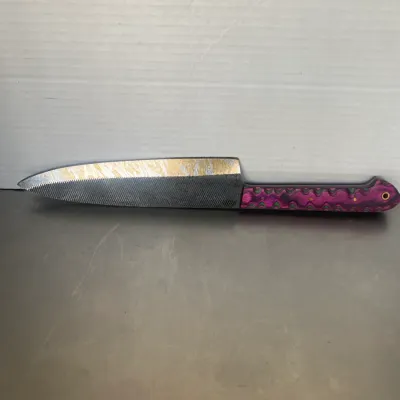Sale Photo Thumbnail #41: Custom handmade knife crafted from a repurposed metal file, featuring a textured blade and a vibrant purple and green laminated wood handle.