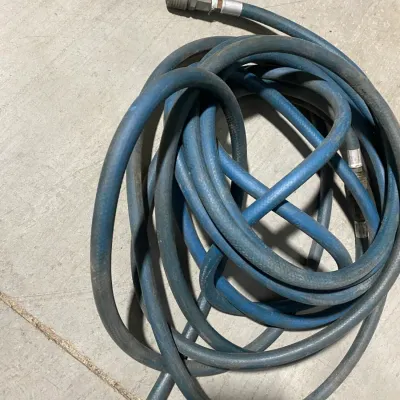 Sale Photo Thumbnail #14: Coiled blue rubber air compressor hose with quick-connect brass fittings, showing some surface wear from use.