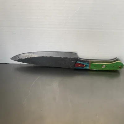 Sale Photo Thumbnail #43: Handcrafted chef's knife featuring a textured steel blade and a vibrant, multi-colored laminated wood handle with brass mosaic pins.