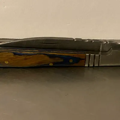 Sale Photo Thumbnail #71: Folding pocket knife featuring a multi-colored wood and blue resin handle with brass pins and a stainless steel bolster.