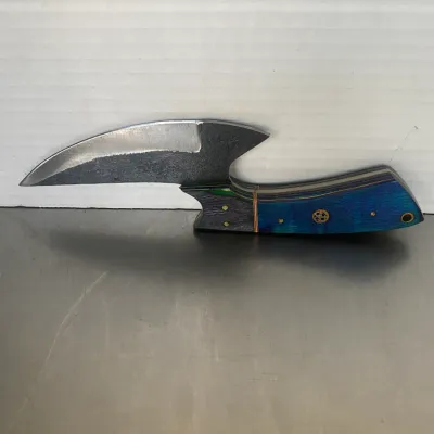 Sale Photo Thumbnail #53: Custom fixed-blade knife featuring a curved, textured steel blade and a vibrant blue and green laminated wood handle with brass mosaic pins.