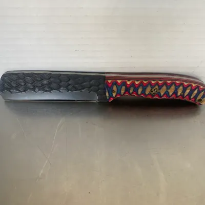 Sale Photo Thumbnail #28: Custom straight razor with a textured, scale-patterned spine and a vibrant, multi-colored laminated wood handle.
