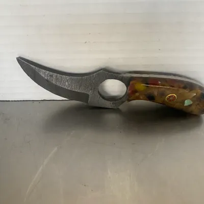 Sale Photo Thumbnail #55: Custom Damascus steel knife featuring a curved blade with a finger hole and a decorative composite handle inlaid with colorful stones and a mosaic pin.