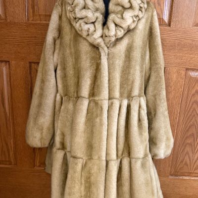 Sale Photo Thumbnail #270: A stylish Jones New York faux fur coat in a warm honey-blonde/tan color. Features a textured, ruffled collar, tiered panel design, and a smooth satin-like lining. Includes a gold-tone chain hanging loop. Size Large (L). Made in China. Appears to be in ver