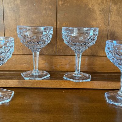 Sale Photo Thumbnail #118: A set of four vintage clear pressed glass champagne coupe or sherbet glasses. Features a textured diamond/honeycomb pattern on the bowl, a faceted stem, and a hexagonal base. Each glass measures approximately 4.5 inches tall. All pieces appear to be in go