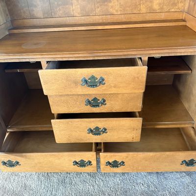 Sale Photo Thumbnail #11: A vintage two-piece wooden hutch featuring a top cabinet with louvered doors, open shelving, and plate grooves, sitting on a base with three central dovetail drawers, two side cabinets, and two wide bottom drawers. Features classic brass-toned hardware. P