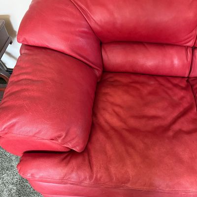 Sale Photo Thumbnail #95: A vibrant red leather loveseat by Natuzzi. Features plush, overstuffed armrests and back cushions. Shows some light wear and creasing consistent with gentle use, but remains in good, comfortable condition. Includes original Natuzzi documentation. Measures