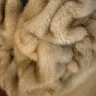 Sale Photo Thumbnail #272: A stylish Jones New York faux fur coat in a warm honey-blonde/tan color. Features a textured, ruffled collar, tiered panel design, and a smooth satin-like lining. Includes a gold-tone chain hanging loop. Size Large (L). Made in China. Appears to be in ver