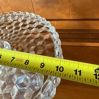 Sale Photo Thumbnail #50: A vintage clear pressed glass pedestal cake stand featuring the classic Fostoria 'American' 3D cube pattern. Features a scalloped, draped rim and a textured, flared pedestal base. Excellent condition with no visible chips, cracks, or clouding. Measures ap