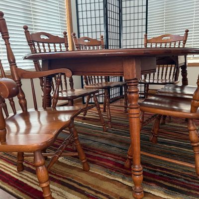 Sale Photo Thumbnail #3: NOT CHERRY IN COLOR.  A classic wooden dining set featuring an oval extension table and six matching Windsor-style chairs. The set includes two armchairs and four side chairs, all featuring turned spindle backs and legs. The table measures approximately 7