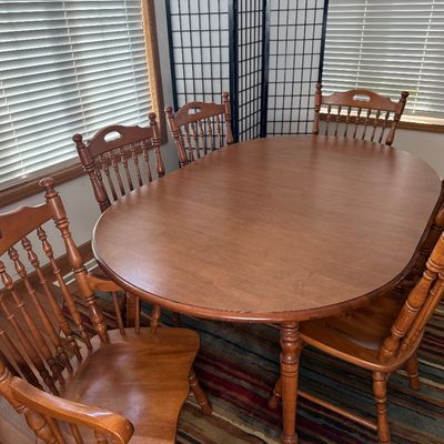Sale Photo Thumbnail #2: NOT CHERRY IN COLOR.  A classic wooden dining set featuring an oval extension table and six matching Windsor-style chairs. The set includes two armchairs and four side chairs, all featuring turned spindle backs and legs. The table measures approximately 7