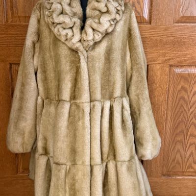 Sale Photo Thumbnail #271: A stylish Jones New York faux fur coat in a warm honey-blonde/tan color. Features a textured, ruffled collar, tiered panel design, and a smooth satin-like lining. Includes a gold-tone chain hanging loop. Size Large (L). Made in China. Appears to be in ver