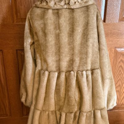 Sale Photo Thumbnail #268: A stylish Jones New York faux fur coat in a warm honey-blonde/tan color. Features a textured, ruffled collar, tiered panel design, and a smooth satin-like lining. Includes a gold-tone chain hanging loop. Size Large (L). Made in China. Appears to be in ver