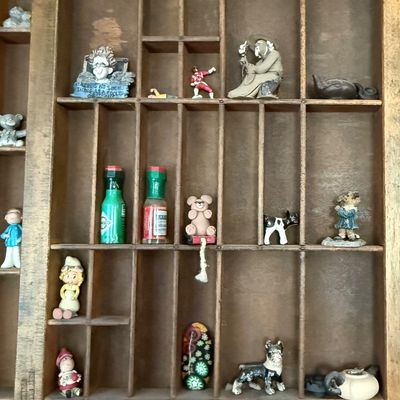 Sale Photo Thumbnail #196: A vintage wooden printer's type drawer repurposed as a hanging shadow box display case. Measures approximately 32 inches wide by 16.5 inches tall. The lot includes a large assortment of miniature collectibles, figurines, and novelty items as shown, includ