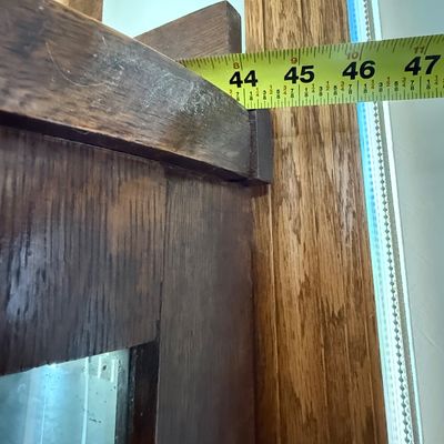 Sale Photo Thumbnail #189: An antique tiger oak china display cabinet featuring a curved glass front door and curved glass side panels. The cabinet includes five wooden shelves, a mirrored upper back section, and elegant carved wood details. It is fitted with a vintage brass and fa