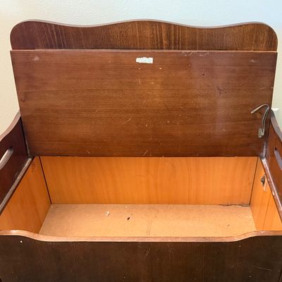 Sale Photo Thumbnail #238: A vintage wooden storage bench featuring a decorative spindle backrest, side handle cutouts, and a hinged seat that opens to a spacious storage compartment. The piece shows some light surface wear, minor scratches, and scuffs consistent with age and use. 