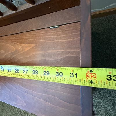 Sale Photo Thumbnail #239: A vintage wooden storage bench featuring a decorative spindle backrest, side handle cutouts, and a hinged seat that opens to a spacious storage compartment. The piece shows some light surface wear, minor scratches, and scuffs consistent with age and use. 