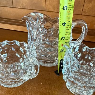 Sale Photo Thumbnail #134: A 3-piece set of vintage clear pressed glass tableware in the classic 'American' pattern by Fostoria (or similar cube/geometric design). The set includes a small pitcher/creamer measuring approximately 4.5 inches tall, a smaller creamer, and a double-hand