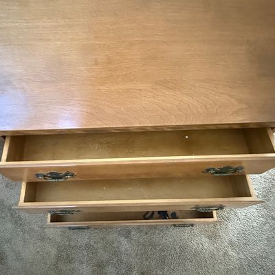 Sale Photo Thumbnail #164: A vintage wooden slant-front secretary desk featuring a drop-down writing surface that opens to reveal an interior organizer with small drawers and mail slots. The lower section includes three large drawers and a row of four smaller drawers, all accented 