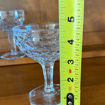 Sale Photo Thumbnail #120: A set of four vintage clear pressed glass champagne coupe or sherbet glasses. Features a textured diamond/honeycomb pattern on the bowl, a faceted stem, and a hexagonal base. Each glass measures approximately 4.5 inches tall. All pieces appear to be in go