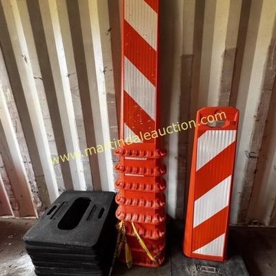 Sale Photo Thumbnail #31: Stack of orange and white reflective vertical panel barricades with heavy black rubber bases, showing some wear from outdoor use.