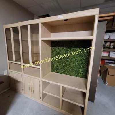 Sale Photo Thumbnail #5: Large light wood entertainment center and display wall unit, featuring glass-front cabinets with shelves on the left and open shelving with a green textured backing on the right.