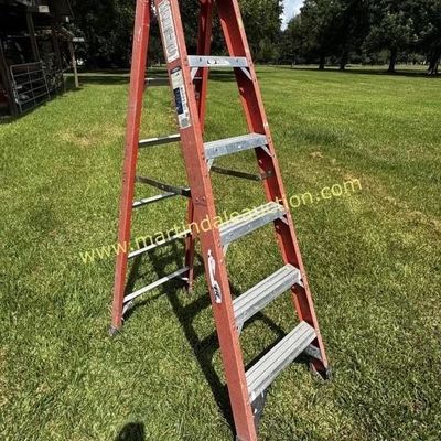 Sale Photo Thumbnail #27: Werner 6-foot orange fiberglass A-frame step ladder with aluminum rungs, showing some outdoor wear.