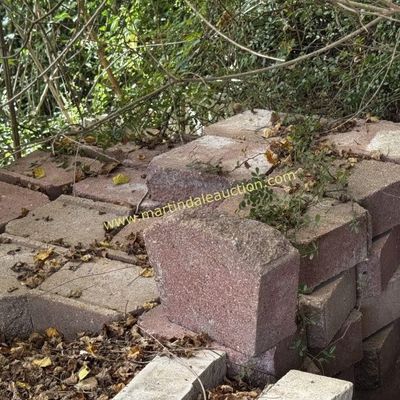 Sale Photo Thumbnail #9: Stack of red concrete retaining wall blocks, showing some weathering and organic debris.