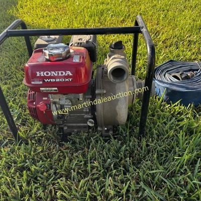 Sale Photo Thumbnail #21: Honda WB20XT 2-inch water pump with roll cage frame, accompanied by a coiled blue discharge hose.