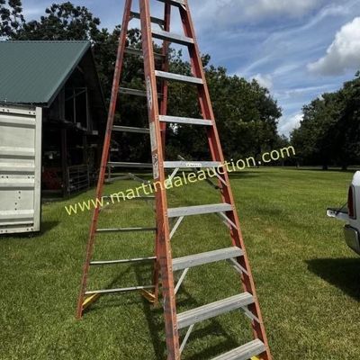 Sale Photo Thumbnail #28: Werner 10-foot orange fiberglass A-frame stepladder with aluminum rungs and a yellow top cap, showing moderate outdoor wear.