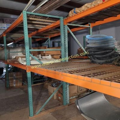 Sale Photo Thumbnail #60: Heavy-duty industrial pallet racking with green uprights, orange crossbeams, and wire mesh decking, showing some wear from warehouse use.