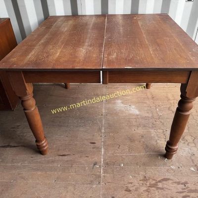Sale Photo Thumbnail #7: Vintage oak dining table with turned legs and a split top designed to accommodate extension leaves, showing some surface wear and scratches.