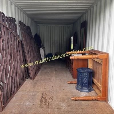 Sale Photo Thumbnail #38: Assorted furniture and architectural salvage stored in a shipping container, including large decorative iron gates, a wooden table, a blue garden stool, and various dressers.