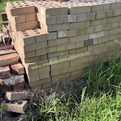 Sale Photo Thumbnail #48: Large stack of tan construction bricks with holes, alongside a smaller pile of weathered red bricks.