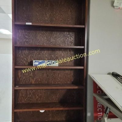 Sale Photo Thumbnail #53: Tall wooden bookcase with a dark finish, featuring six spacious shelves and a prominent wood grain backing.