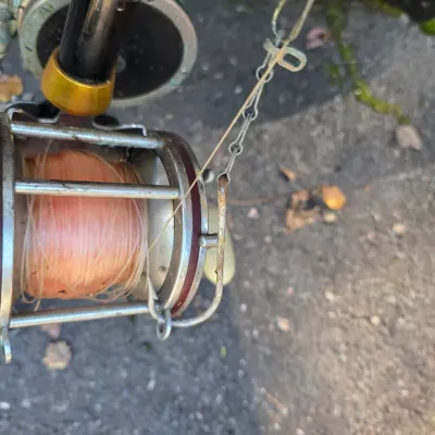 Sale Photo Thumbnail #36: Vintage Penn conventional fishing reel spooled with line, showing some wear and oxidation from use.