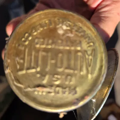 Sale Photo Thumbnail #26: Vintage brass Auto-Lite carbide miners lamp, showing the embossed manufacturer details on the bottom of the canister.