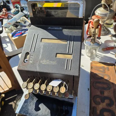 Sale Photo Thumbnail #43: Vintage National cash register with a black textured finish, chrome accents, and round key buttons, showing some wear and rust.