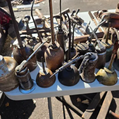 Sale Photo Thumbnail #21: Collection of vintage metal oil cans in various shapes, sizes, and conditions, showing significant patina and rust.