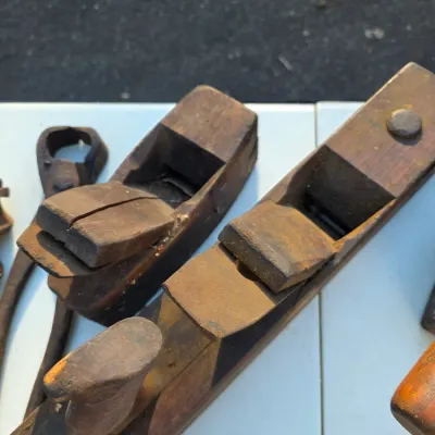 Sale Photo Thumbnail #32: Two antique wooden hand planes showing significant wear and patina from age and use.