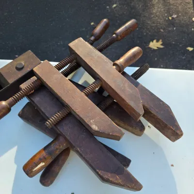 Sale Photo Thumbnail #33: Stack of vintage wooden hand screw clamps, showing a weathered patina and signs of use.