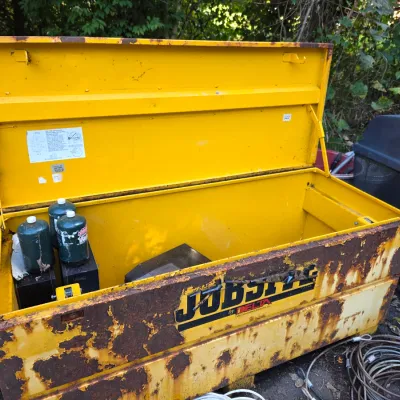 Sale Photo Thumbnail #38: Heavy-duty yellow Jobsite by Delta steel tool chest, showing significant exterior rust and wear, with an open lid revealing a spacious interior containing small propane tanks.