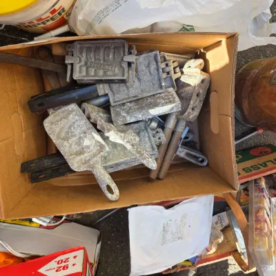 Sale Photo Thumbnail #18: Cardboard box filled with vintage cast aluminum and metal molds, including a Tenn-Sport mold, showing some oxidation and wear.