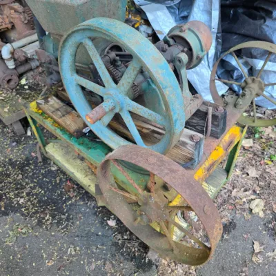 Sale Photo Thumbnail #39: Vintage hit-and-miss engine mounted on a wheeled cart, showing significant rust, weathered blue paint, and aged wooden supports.