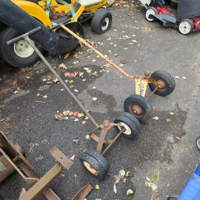 Sale Photo Thumbnail #46: Two vintage Tee-Nee trailer dollies with rubber wheels, shown alongside lawn care equipment.