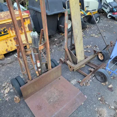 Sale Photo Thumbnail #35: Vintage heavy-duty steel hand trucks and dollies showing significant rust and wear, suitable for industrial or farm use.