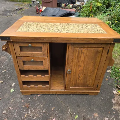 Sale Photo Thumbnail #52: Rustic oak kitchen island featuring a granite inlay top, two drawers, built-in wine racks, an open center cubby, and a single cabinet door.