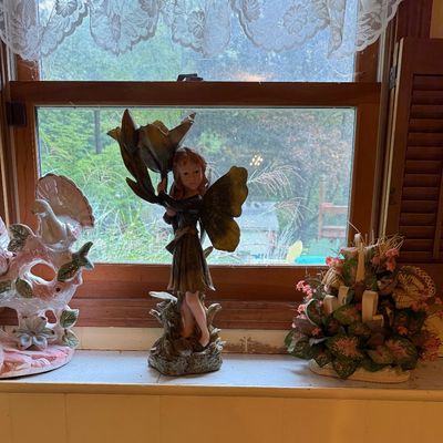 Sale Photo Thumbnail #13: Assorted decorative items on a windowsill, including a ceramic bird figurine, a fairy statue holding a flower, and a small faux floral arrangement.