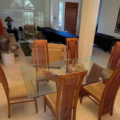 Contemporary dining set featuring a rectangular glass-top table on a wooden base, paired with six high-back wooden chairs with...